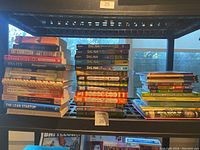 Photo showing three stacks of books including Dog Man series, Diary of a Wimpy Kid series, and various adult non-fiction books.
