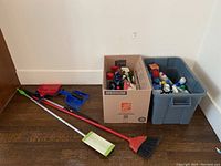Photo showing broom, dustpan set, and cleaning supply boxes on floor