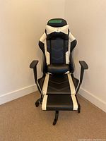 Front view of black and white gaming chair with padded cushions, armrests, and footrest visible.