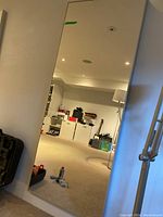 Full view of rectangular mirror leaning against wall showing frame and reflection of room