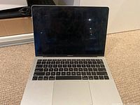 Open MacBook Air showing keyboard, trackpad, and blank screen