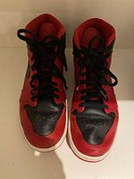 Front view of red and black men's Air Jordan style high-top sneakers with black laces and white soles.