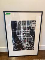 Full view of framed black and white Manhattan map with white matte and black frame.