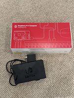 Top view of the Raspberry Pi 4 Computer Desktop Kit box and Nintendo Switch TV dock on carpeted floor.