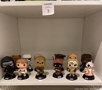 Full view of 12 Star Wars Funko Pop figures arranged on a white shelf.