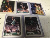 Five basketball trading cards including Ron Mercer and others, laid out on countertop.