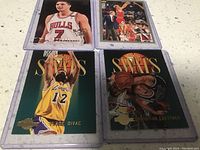Four basketball trading cards featuring Christian Laettner, Vlade Divac, Steve Kerr, and Toni Kukoc, all sleeved and signed