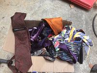 Box containing a variety of men's ties in different colors and patterns viewed from above.