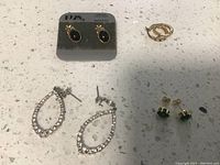 Four pairs of earrings displayed on a white countertop including an attached card for one pair.