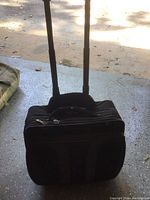 Black rolling luggage bag front view showing extendable handles and zippered compartments