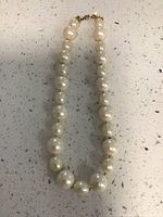 Full view of the pearl necklace laid flat on a countertop showing the strand of pearls.