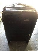 Front view of black Samsonite hard body luggage suitcase, showing textured product surface and telescoping handle on top.