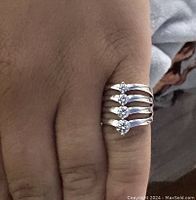 Ring worn on finger showing four separate tiers each set with a round clear stone, size approx 6.5