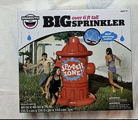 Front view of box showing BigMouth Inc. Big Sprinkler in fire hydrant design with 'SPLASH ZONE' graphic, size details and photo of children playing.