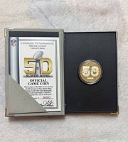 Super Bowl 50 official coin in presentation box with certificate of authenticity partially visible.