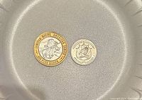 Close-up of two coins, including Native American Centennial .999 pure silver coin and a smaller coin with a ship design