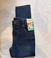 Photo of the dark blue denim jeans folded flat, showing the jeans' front and button.