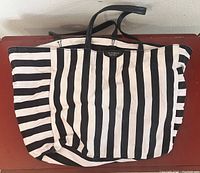 Photo of a large Victoria's Secret tote bag with vertical black and white stripes and black handles