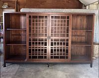 Front view of the closed media cabinet showing solid wood with lattice sliding doors and metal legs.