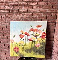 Single canvas print depicting poppy flowers in a field with blue sky background, leaning against brick wall.
