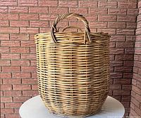 Side view of large woven wicker basket with handle