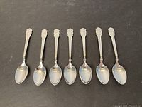 Seven spoons laid out on a black background