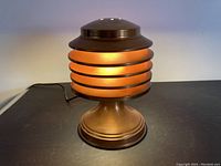 Front view of copper louvered table lamp on black surface