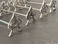 Close-up of the spade-shaped decorated end of the utensil rests showing Art Nouveau style and detail.