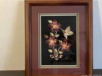 Framed tufting artwork showing floral design and hummingbird on black background.