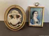 Pair of two framed miniature portrait paintings on display; one oval with ornate filigree frame and one rectangular with simpler gold frame