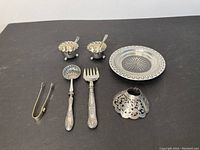 Two footed salt cellars with spoons, pierced bonbon dish, sugar tongs, straining spoon, serving fork and openwork shade