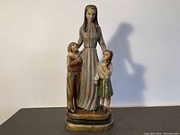 Front view of carved wooden polychromed statue depicting a mother and two children