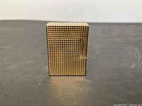 Front view of the gold filled lighter showing the textured engraved pattern with a push lever on the side.