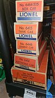 Stack of five original Lionel train car boxes labeled with car types and model numbers.