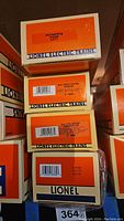 Stack of Lionel Electric Trains original boxes with model and item numbers visible including Erie Operating Hopper 6117 and New Jersey Central Gondola 16943.