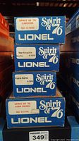 Stacked view of four blue Lionel Spirit of 76 boxes labeled with caboose, New Hampshire box car, Virginia box car, and U36B diesel number.