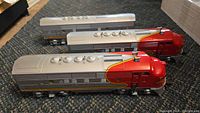 Three-quarter view of both silver and red Santa Fe F3 locomotives side by side on carpet