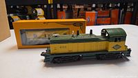 Front and side view of yellow and green Lionel 8153 diesel engine with Reading Lines logo, with original packaging behind.