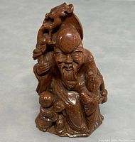 Front view of old Chinese wiseman sculpture carved in goldstone with two children at his feet and detailed facial features.