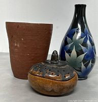 Three pottery items: terracotta planter, floral glazed vase, sandalwood incense burner.