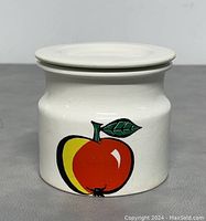 Front view of the vintage Arabia Finland jam jar with colorful apple design on white ceramic body and fitted lid.