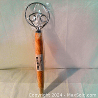 Full view of Danish dough whisk showing the wooden handle with label and circular stainless steel wire whisk head with spiral loops, against a white backdrop.