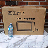 Sealed cardboard box of HOMOKUS Food Dehydrator with 31QT capacity label shown alongside a water bottle for scale.