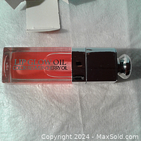 Lip gloss tube showing the product name and oil-based formula in cherry color.