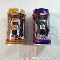 Two mini remote control racing cars inside clear pop can-style packaging, one orange and white, one black and white with green and pink accents.