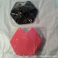 Two new silicone body brushes, one black and one pink, hexagonal shape, wrapped in clear plastic bags.