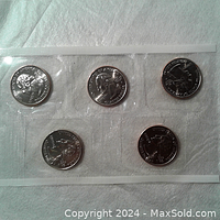 Front side of five quarters in sealed plastic with George Washington profiles.