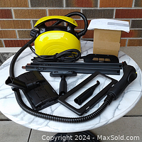 Full set of Waitbird steam cleaner and various attachments displayed on round table for visual inspection.