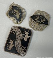 Three Siam sterling silver brooches showing front views with black enamel backgrounds and silver dancing figures.