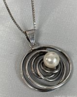 Close-up of pendant showing spiral design and faux pearl center